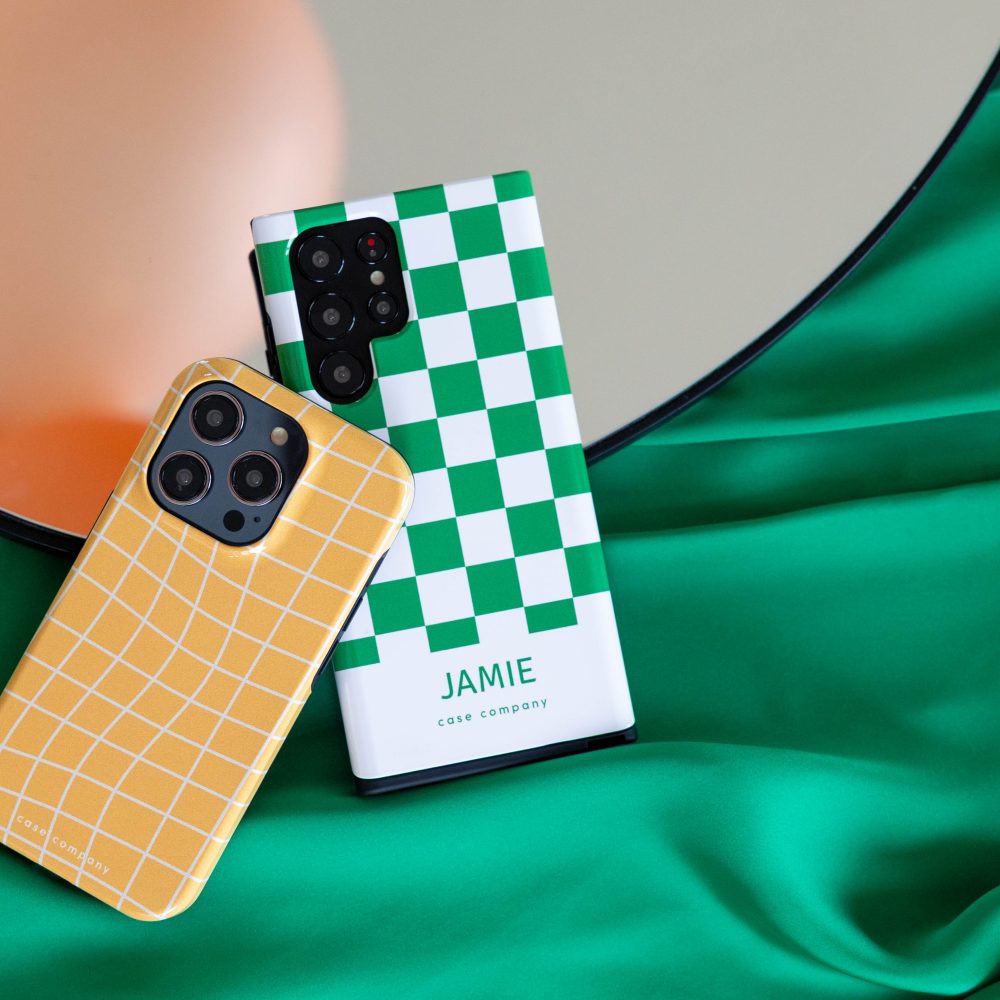 Dvě odolná pouzdra: žluté kostkované pro iPhone a zelené se šachovnicovým vzorem a jménem Jamie